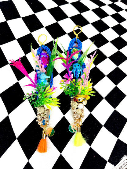 Blue crochet earrings in a long oval shape of 12cm, with a colourful under the sea theme including aquarium plants, glass seahorse, small gravel with seashells real pearl and small tassel. 2nd earring is similarly themed with aquarium plants, blue glass octopus and tiny yellow glass fish, with gravel pearl and tassels