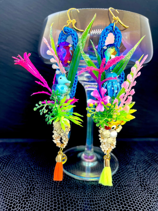 Blue crochet earrings in a long oval shape of 12cm, with a colourful under the sea theme including aquarium plants, glass seahorse, small gravel with seashells real pearl and small tassel. 2nd earring is similarly themed with aquarium plants, blue glass octopus and tiny yellow glass fish, with gravel pearl and tassels